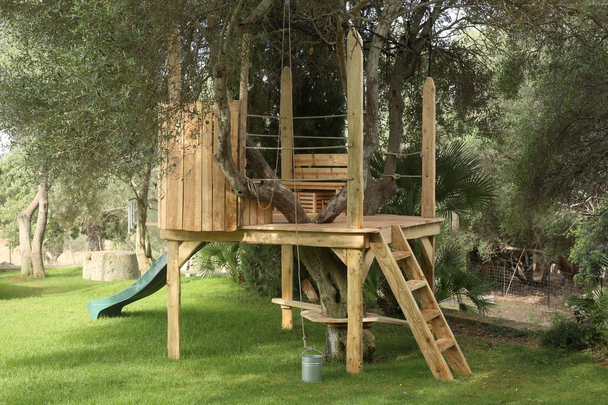 Casa de árbol con cabaña y tobogán, jardín mediterráneo